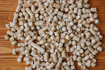 Biofuel - small wooden pellets over the wooden table.
