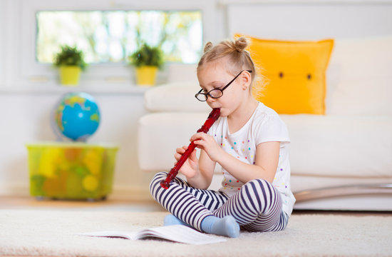 Portrait of pretty little girl with flute on floor