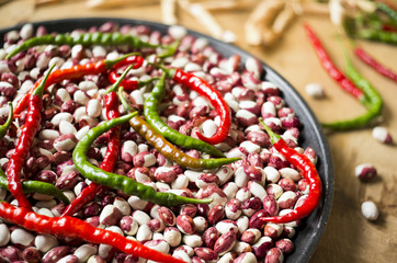 Lots of chili peppers and beans on the wooden surface. Selective focus.