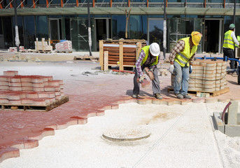 Construction workers paving a sidewalk with concrete pavers
