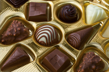 Assortment of fine chocolate candies pralines, white, dark, and milk chocolate in golden box. Product concept for patisserie. Top View