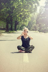 Fototapeta premium Woman sitting with crossed legs in the middle of the street, making heart shape with her hands