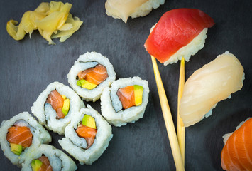 Sushi and Sashimi rolls on a black stone slatter. Fresh made Sushi set with salmon, prawns, wasabi and ginger. Traditional Japanese cuisine..