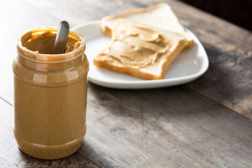 Peanut butter jar and toasts on wooden table. Copyspace.
