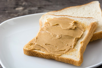 Peanut butter and toasts on wooden table.
