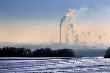 Krajobraz zimowy, dymiące kominy fabryki.