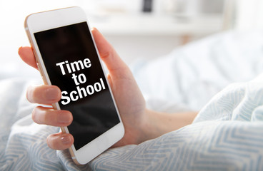 Time to School on smart phone screen, girl lying in bed