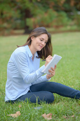 Obraz premium Woman sat in park writing in notepad