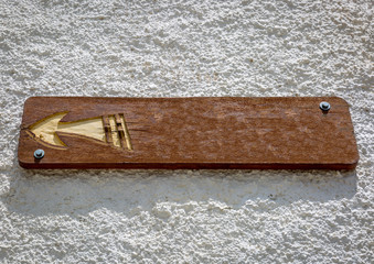 Wooden sign with an arrow, on a whitewall