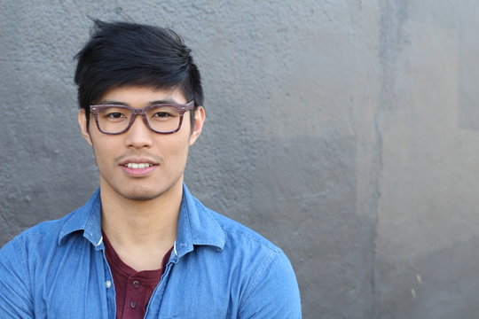 Young Asian male with glasses smiling with copy space 