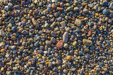 Beautiful colorful pebble stones on beach California background pattern texture