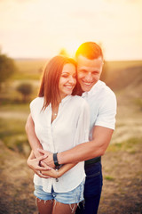 Happy couple holding hands and walking together outdoors at sunset