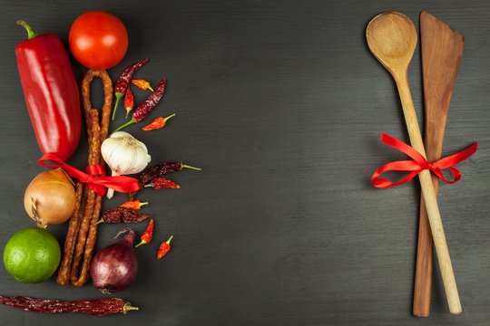 Wooden spoons and vegetables on a black table. Food preparation. Decoration advertising the restaurant.
