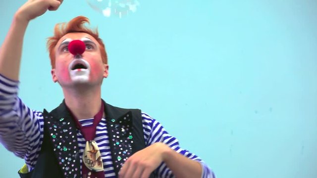 Big adult clown playng with soap bubbles