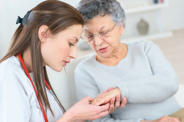 Carer examining elderly lady's hand