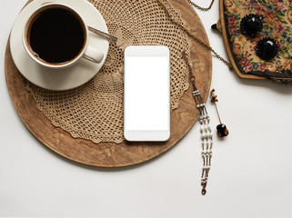 Top view on a cup of coffee on a wooden tray, smartphone with blank copy space screen, antique...