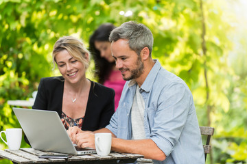 Fototapeta premium A smart couple is sitting at a terrace cafe and using a laptop