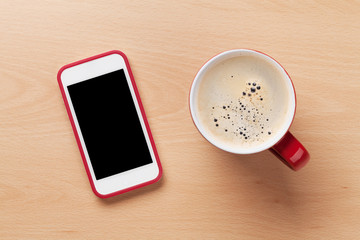 Coffee cup and smartphone on wooden desk