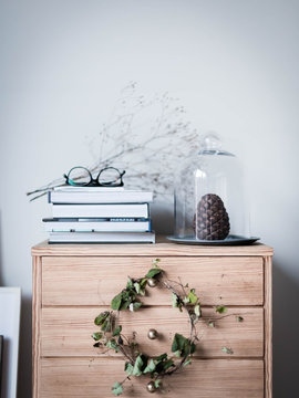 Stack of books and pinecone on wooden cabinet
