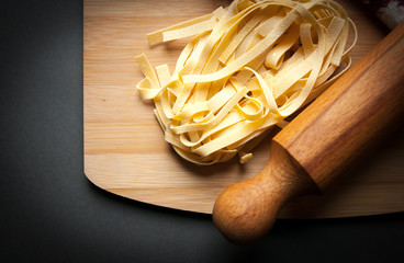 italian tagliatelle displayed on a chopping board together with some ingredients