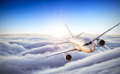 Fototapeta na wymiar Airplane flying above clouds in dramatic sunset