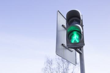 Traffic lights with active green against the sky