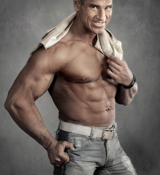 Muscular smiling shirtless man against gray background