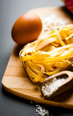 italian tagliatelle displayed on a chopping board together with some ingredients