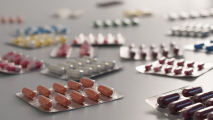 set of multicolored tablets and capsules in the package located on a white background close up