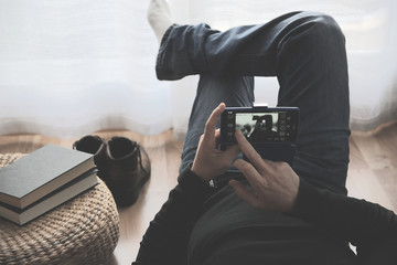 Young man lying while using his mobile after reading a book. Copy space for Editor's text.