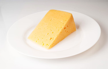 A piece of cheese on a plate isolated on white background milk p