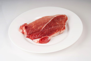 A piece of raw meat steak on a plate isolated on white backgroun
