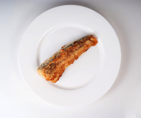 A piece of fried marine fish hake on a plate isolated on white b