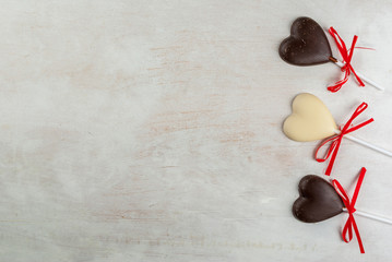 Valentine's Day background: white wooden table with candy in the form of hearts on a stick, with...