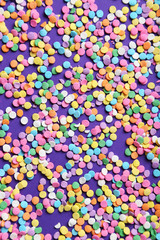 Colorful sprinkles on the purple background