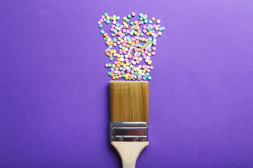 Colorful sprinkles with paintbrush on the purple background