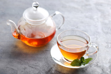 Cup of tea with mint leaf on grey wooden table
