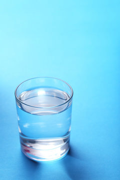 Glass with water on blue background