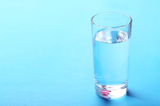 Glass with water on blue background