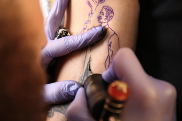 Professional artist making tattoo in salon, close up view