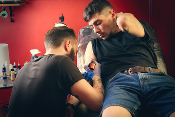 Professional artist making tattoo in salon