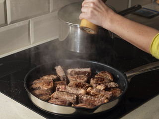Frying beef on frying pan, adding salt.