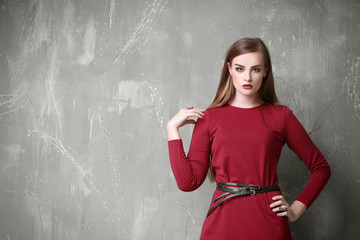 Attractive woman in red gown with beautiful makeup posing on grey background
