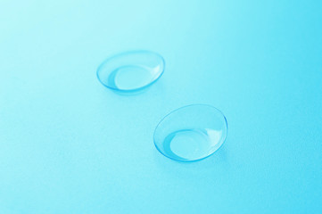 Pair of contact lenses on blue background, close up view