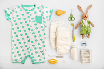 Baby care accessories and clothing on light background, top view
