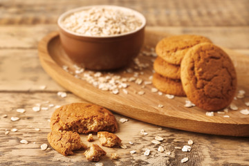 Oatmeal cookies and bowl with groats on wooden table