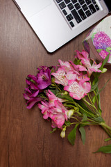 Laptop on wood floor with flowers. alstroemeria