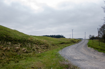 A winding gravel road leading to a grey sky
