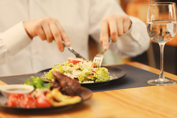 Obraz na płótnie Canvas Client eating tasty Caesar salad in restaurant, close up