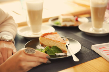 Close up view of young woman sitting in cafe with dessert and drinks